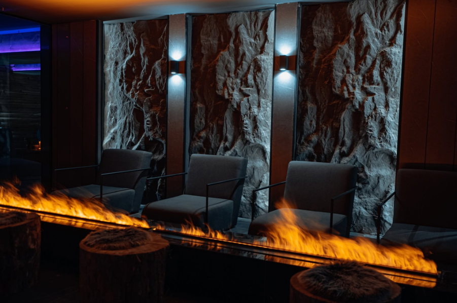Зона за релакс с декоративна камина и каменна стена в Pulse Therme Bansko.